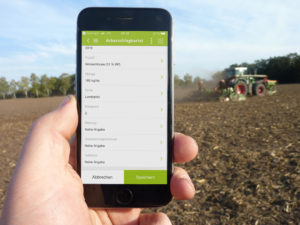 Handy mit Ackerschlagkartei App vor Feld