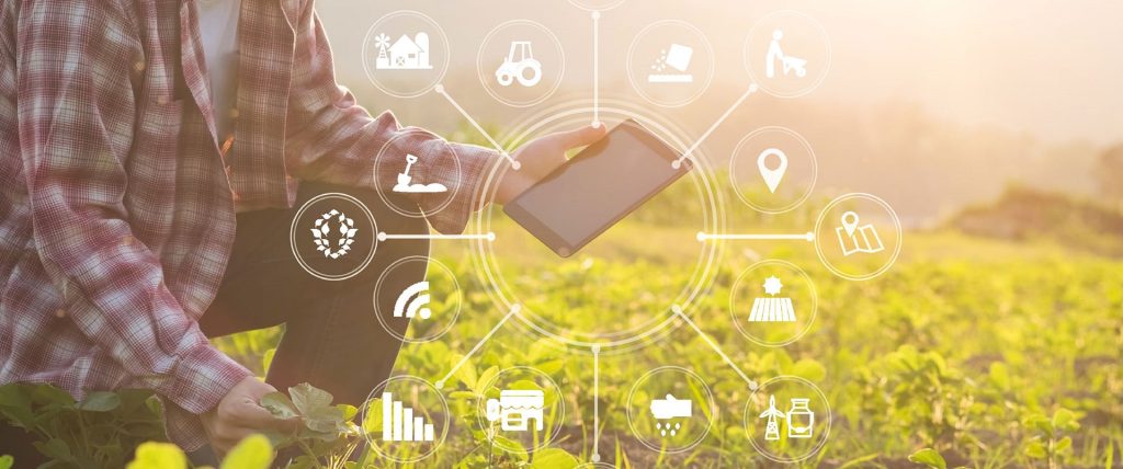 Ein Landwirt hält auf einem Feld ein Tablet in der Hand. Anhand von Symbolen wird verdeutlicht, wie viele Funktionen er damit an der Hand hat.